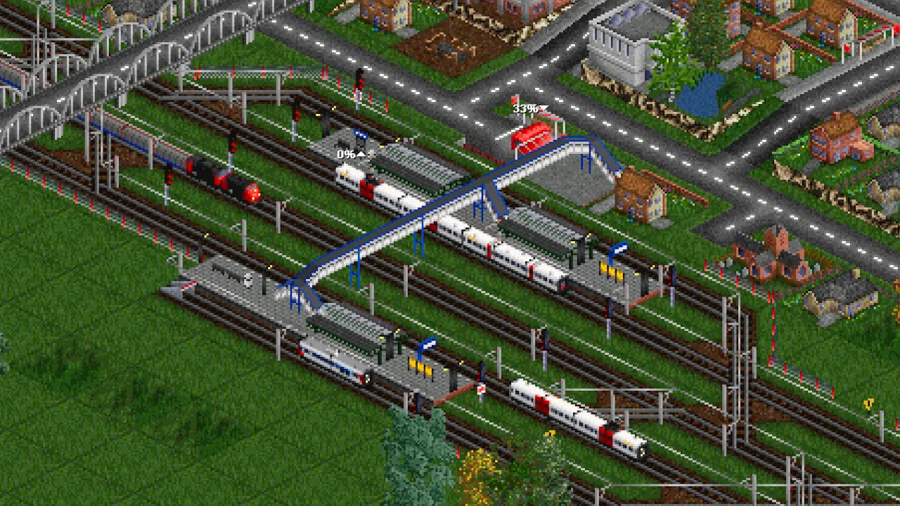 OpenTTD trains waiting at a busy electrified station with a footbridge over the tracks